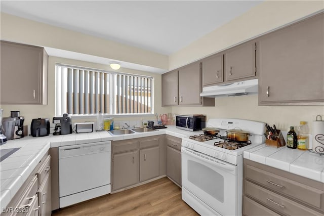 5530 Berchmans Ave, Las Vegas, NV 89122 - kitchen featuring under cabinet range hood, a sink, tile countertops, and white appliances