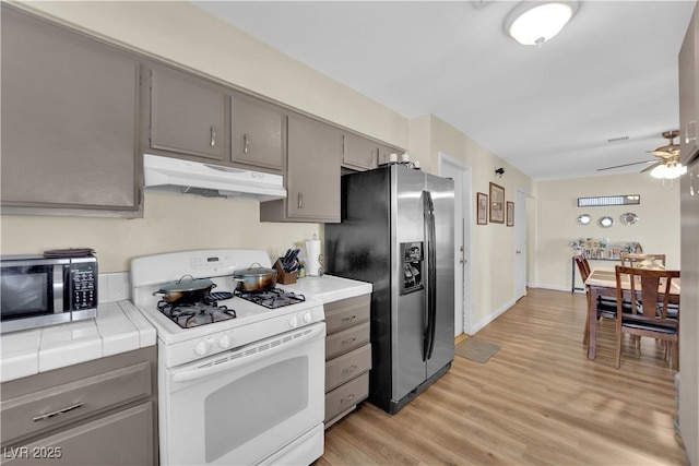 5530 Berchmans Ave, Las Vegas, NV 89122 - kitchen with a ceiling fan, tile counters, stainless steel appliances, under cabinet range hood, and gray cabinetry