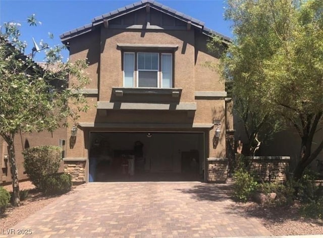 view of front of home featuring stucco siding, a tiled roof, decorative driveway, and an attached garage