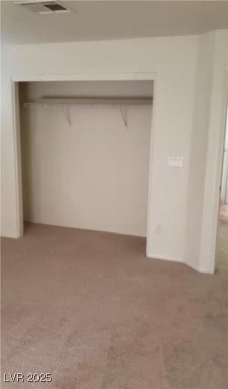 unfurnished bedroom with visible vents, a closet, and light carpet