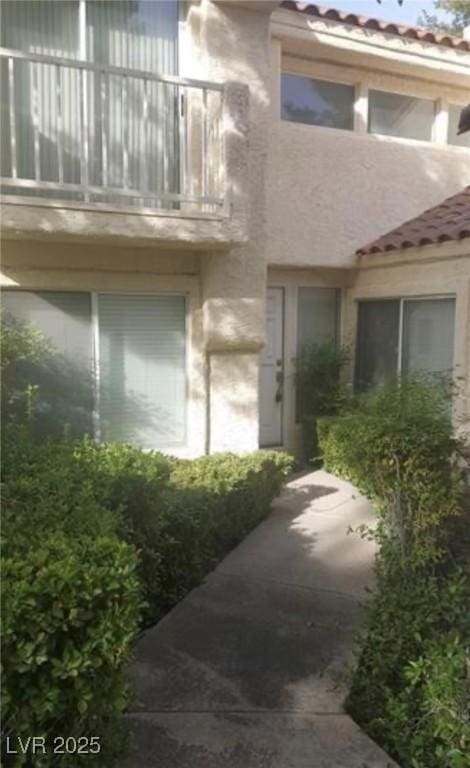6974 Emerald Springs Ln, Las Vegas, NV 89113 - view of exterior entry with stucco siding, a tile roof, and a balcony