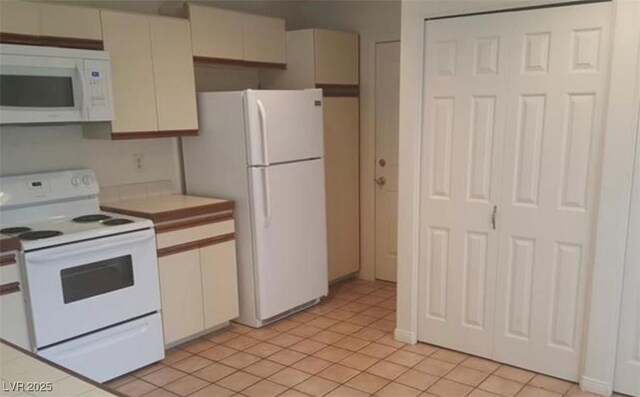 6974 Emerald Springs Ln, Las Vegas, NV 89113 - kitchen with white cabinets, light tile patterned floors, light countertops, and white appliances