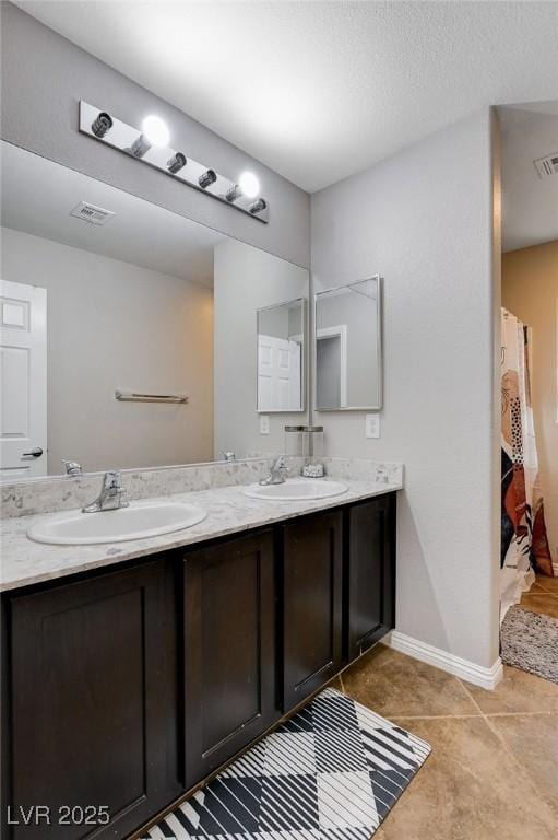 full bath with double vanity, baseboards, and tile patterned floors
