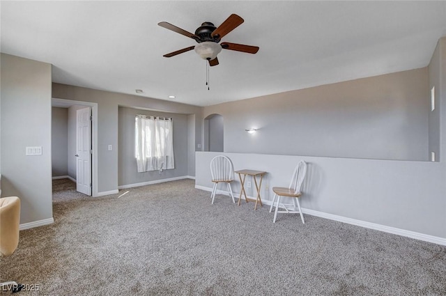 sitting room featuring ceiling fan, carpet, baseboards, and arched walkways