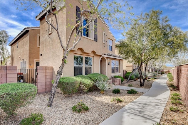 view of front of house featuring stucco siding, fence, and a gate