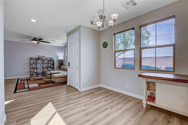 interior space featuring light wood-style flooring, baseboards, ceiling fan, a chandelier, and recessed lighting