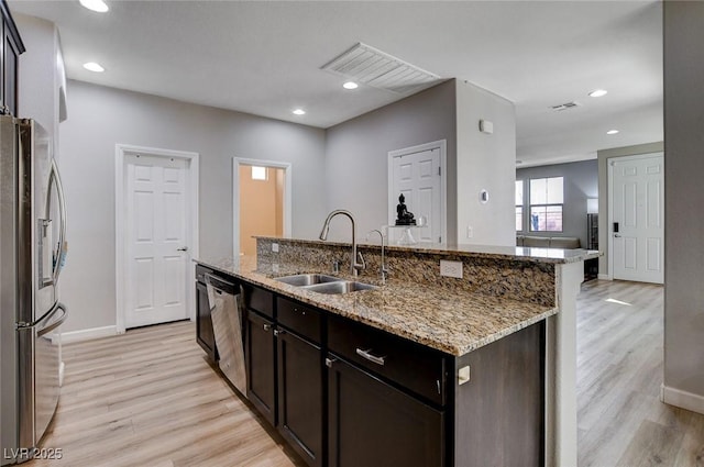 11036 Mount Hunter St, Las Vegas, NV 89179 - kitchen featuring stainless steel appliances, light wood-type flooring, a kitchen island with sink, recessed lighting, and light stone countertops