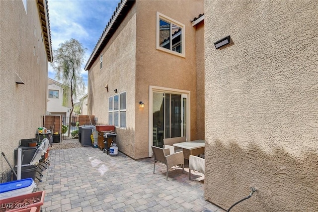 rear view of house featuring stucco siding, central AC unit, a patio area, and fence