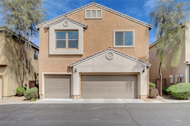 view of property featuring an attached garage, stucco siding, a tiled roof, and driveway