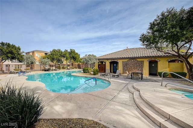 community pool with a patio and fence