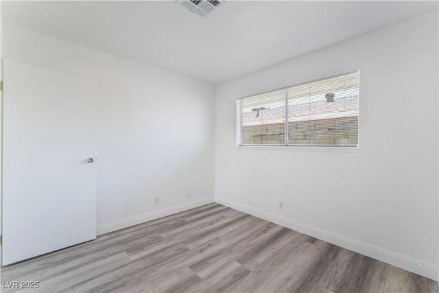 spare room with visible vents, baseboards, and light wood finished floors