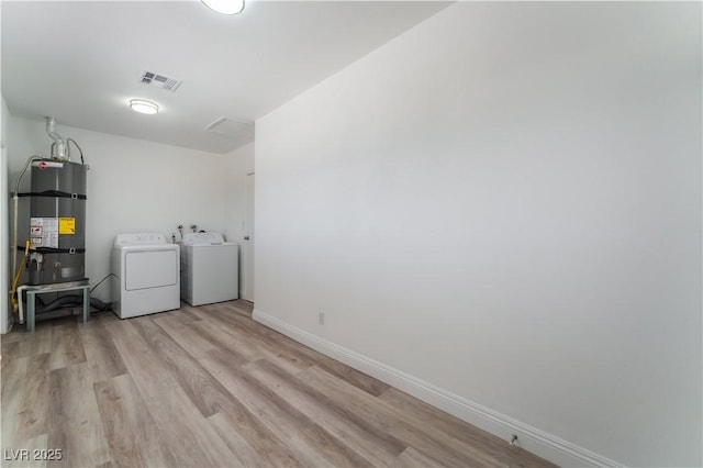 laundry area with visible vents, strapped water heater, light wood-style floors, laundry area, and independent washer and dryer