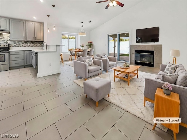 living area featuring light tile patterned floors, visible vents, lofted ceiling, a tile fireplace, and ceiling fan