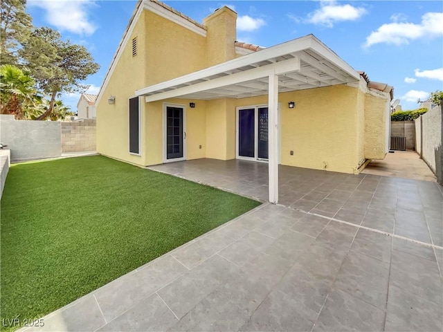 rear view of property featuring a fenced backyard, stucco siding, a tile roof, and a lawn