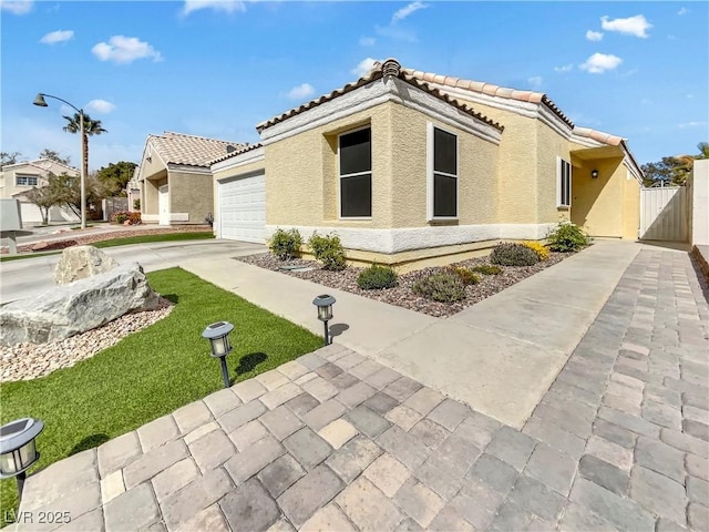 view of front of house featuring an attached garage, a tiled roof, concrete driveway, and stucco siding