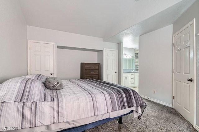 carpeted bedroom with ensuite bathroom and baseboards