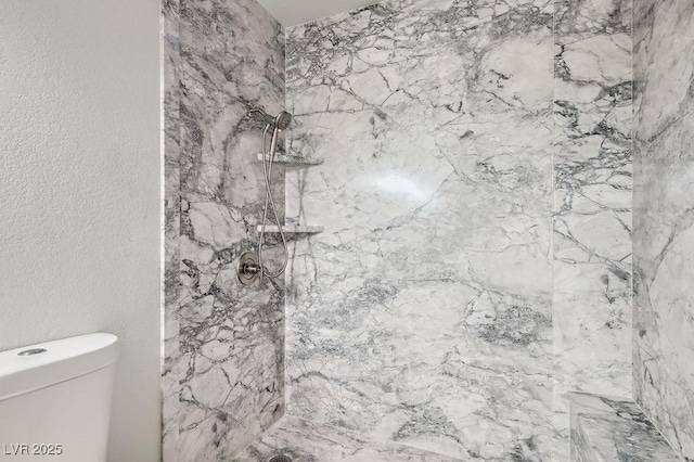 bathroom with a marble finish shower, toilet, and a textured wall