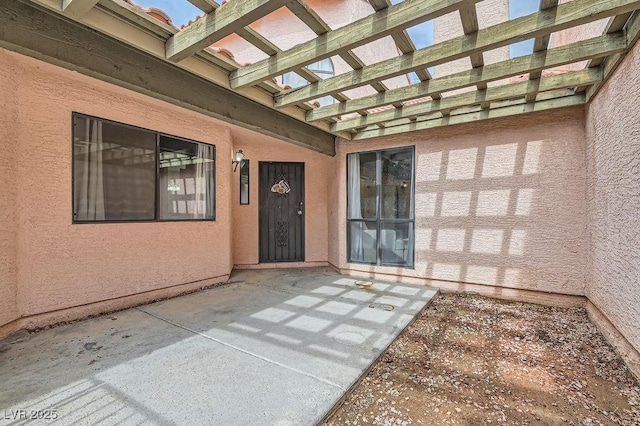 entrance to property with a patio, a pergola, and stucco siding