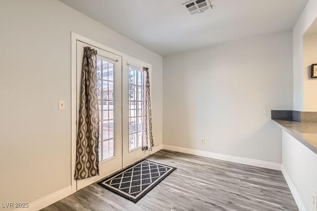 doorway to outside featuring visible vents, baseboards, and wood finished floors