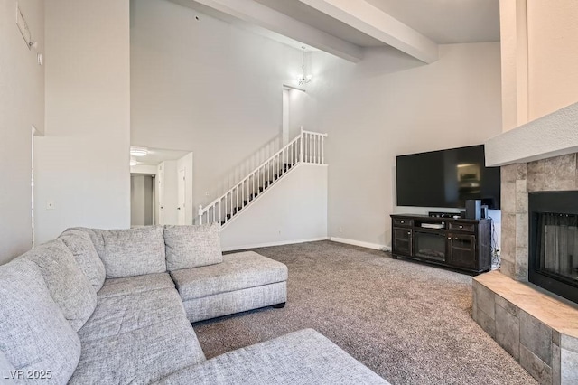living room with beamed ceiling, a towering ceiling, carpet flooring, a tiled fireplace, and baseboards
