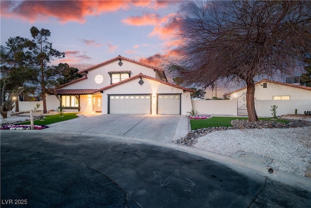 mediterranean / spanish house featuring driveway, fence, an attached garage, and a tile roof