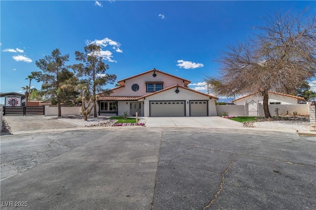 mediterranean / spanish-style house featuring stucco siding, fence, a gate, an attached garage, and driveway