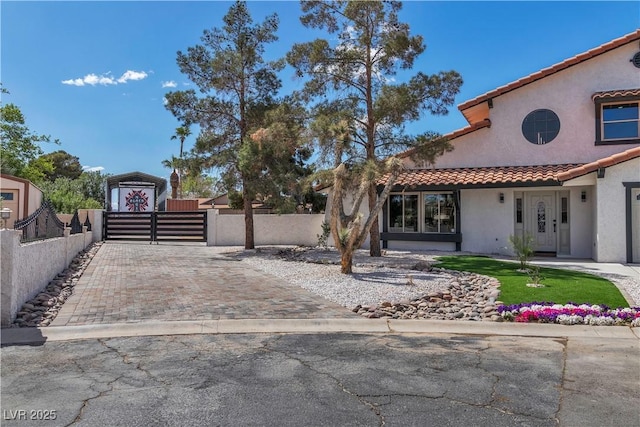 view of front of house with a tile roof, stucco siding, a gate, and a fenced front yard