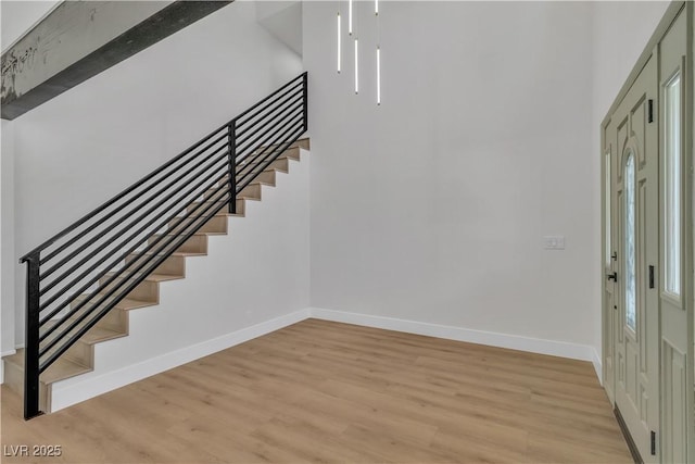 entrance foyer with light wood-style floors, baseboards, and stairs