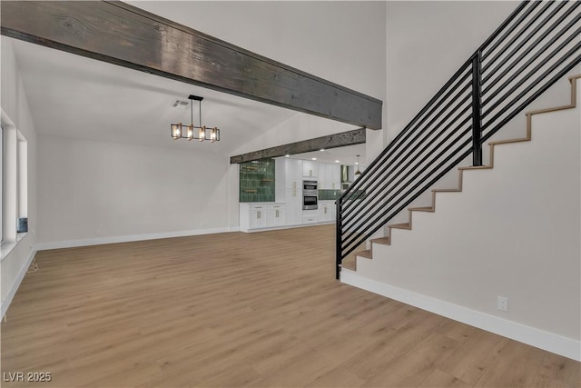 interior space featuring an inviting chandelier, stairway, light wood finished floors, baseboards, and beam ceiling