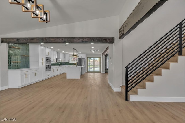 unfurnished living room with light wood finished floors, a sink, and stairway