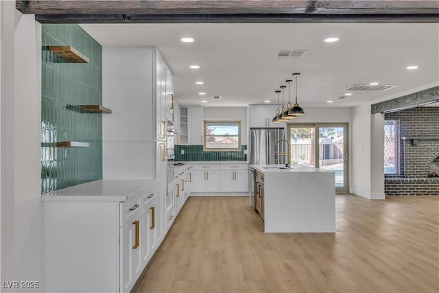kitchen with light wood-style flooring, light countertops, white cabinetry, and stainless steel appliances