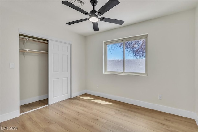 unfurnished bedroom featuring a closet, light wood-style flooring, a ceiling fan, and baseboards