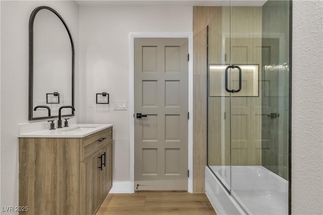 bathroom with shower / bath combination with glass door, vanity, and wood finished floors