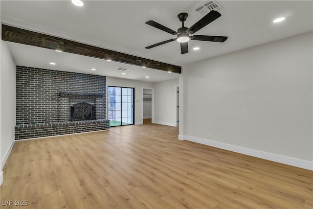unfurnished living room featuring baseboards, light wood-style floors, beam ceiling, and visible vents
