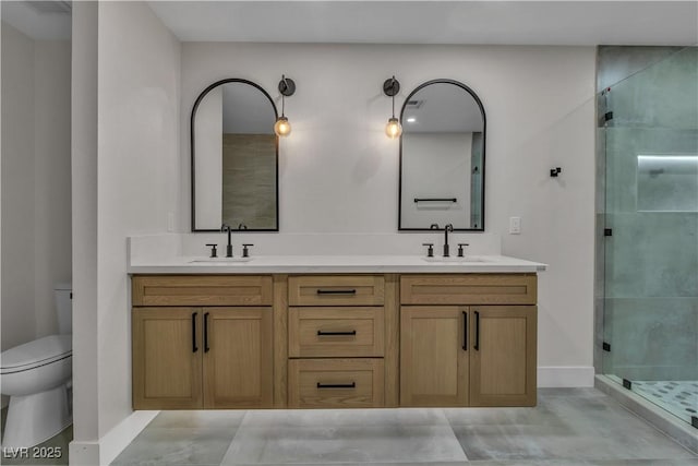 bathroom featuring a shower stall, double vanity, a sink, and toilet