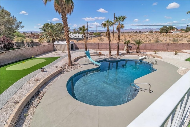 view of pool featuring a fenced in pool, a fenced backyard, a water slide, and a patio area