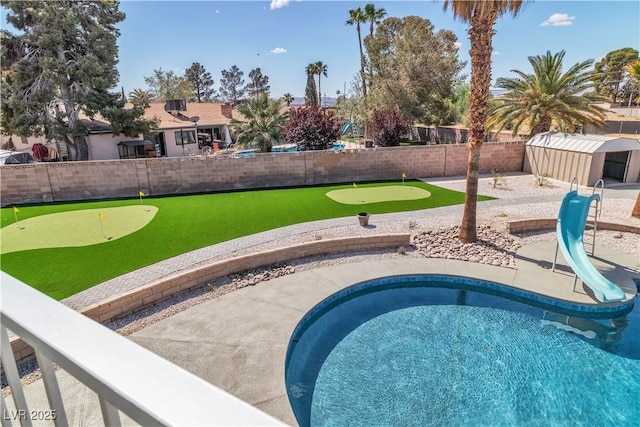 view of pool with a fenced in pool, a patio, a water slide, a fenced backyard, and a storage unit
