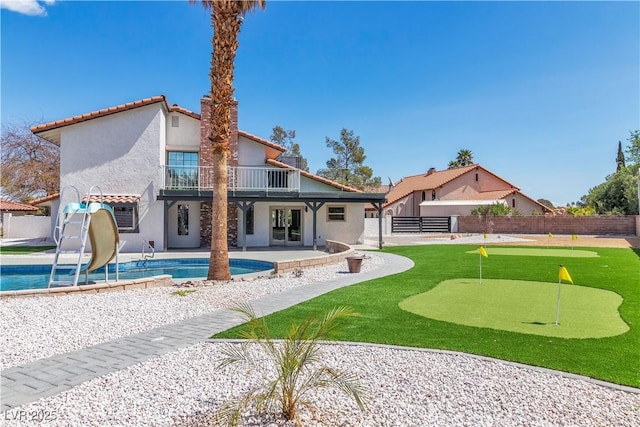 back of house with a fenced backyard, stucco siding, a patio area, a balcony, and a fenced in pool