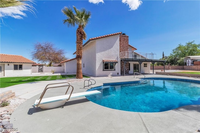 view of pool featuring a fenced in pool, a patio, a diving board, fence, and a lawn