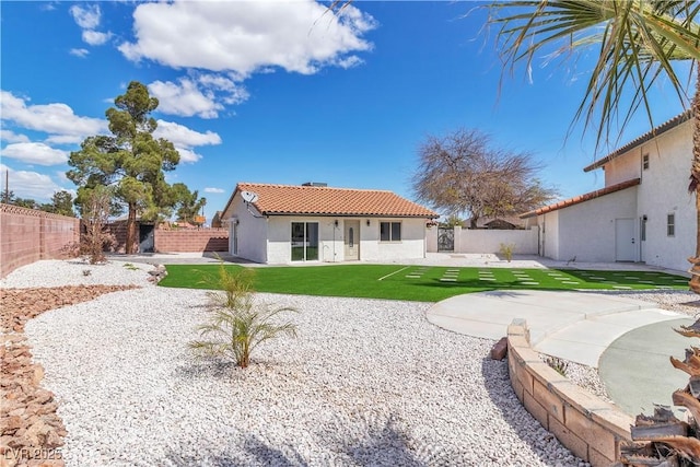 back of property with a tiled roof, a fenced backyard, a yard, and a patio