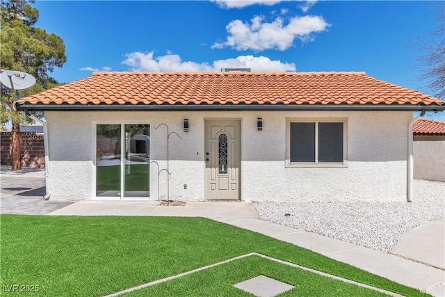 mediterranean / spanish-style home with a patio, stucco siding, a front yard, and a tile roof