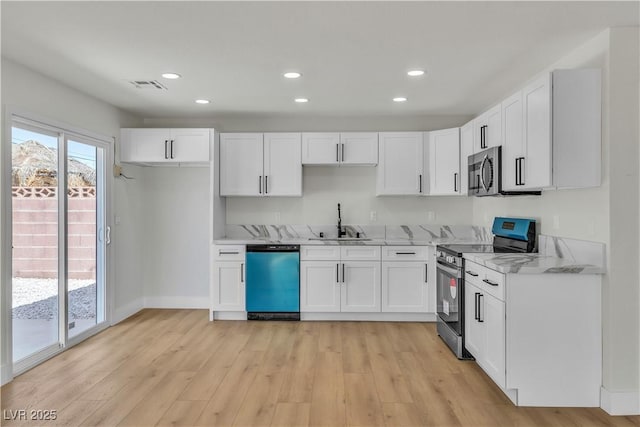 kitchen featuring light wood-style flooring, white cabinetry, visible vents, appliances with stainless steel finishes, and a sink