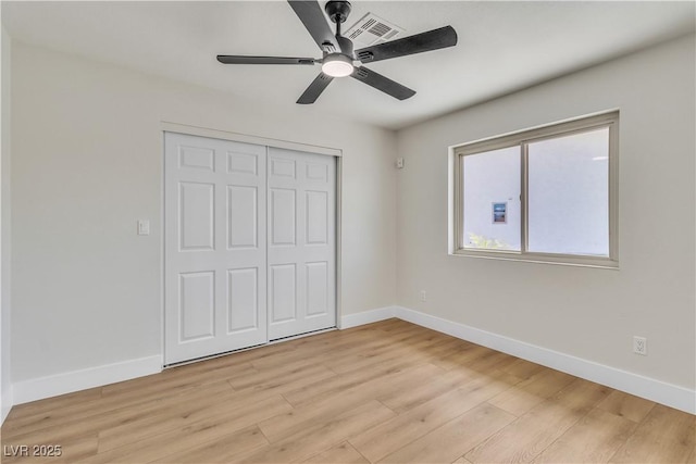 unfurnished bedroom with a closet, baseboards, light wood-style flooring, a ceiling fan, and visible vents