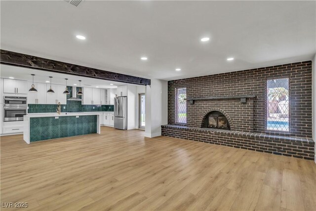 unfurnished living room featuring a sink, light wood-style floors, and a healthy amount of sunlight