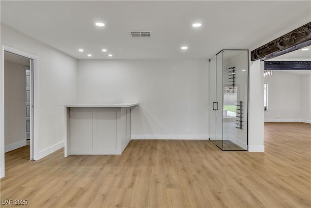 empty room with light wood-style floors, recessed lighting, visible vents, and baseboards