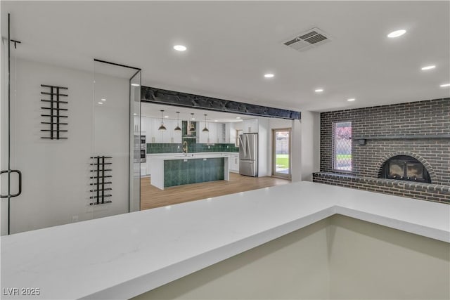 kitchen with visible vents, a sink, light countertops, freestanding refrigerator, and recessed lighting
