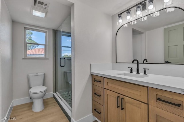 bathroom with vanity, toilet, a shower stall, visible vents, and wood finished floors