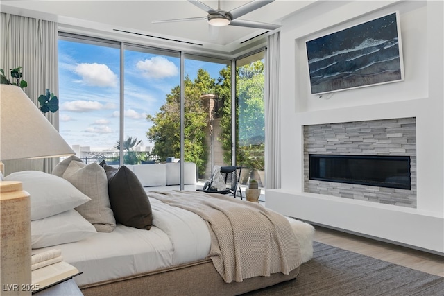 667 Palisade Rim Dr, Henderson, NV 89012 - bedroom with wood finished floors, a glass covered fireplace, a ceiling fan, and a wall of windows