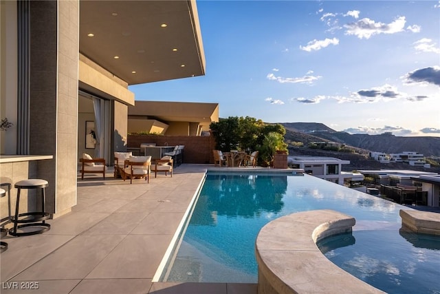 667 Palisade Rim Dr, Henderson, NV 89012 - view of swimming pool with a mountain view, a pool with connected hot tub, and a patio