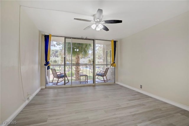 725 N Royal Crest Cir Unit 214, Las Vegas, NV 89169 - empty room with floor to ceiling windows, a ceiling fan, wood finished floors, and baseboards